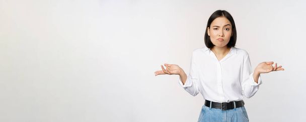 Kuva sekava aasialainen toimistopäällikkö, toimisto nainen kohauttaa olkapäät ja etsivät tietämätön, seisoo ymmällään valkoista taustaa vasten - Valokuva, kuva
