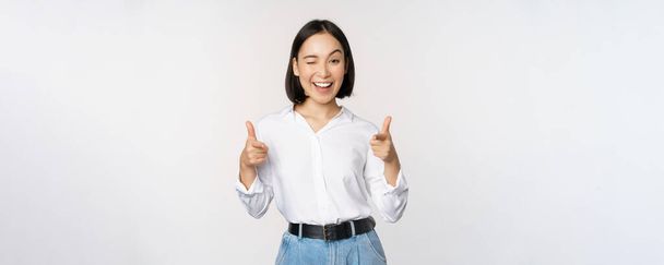 Sein Glückwunsch. Lächelnde attraktive Asiatin, Geschäftsfrau zeigt mit zufriedenem Gesicht mit dem Finger in die Kamera, gratuliert, lädt ein, steht über weißem Hintergrund - Foto, Bild