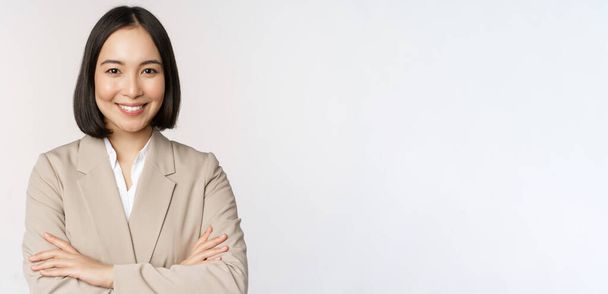 Zelfverzekerde vrouwelijke ondernemer, aziatische zakenvrouw aan de macht poseren, professionele zakenman, kruis armen op de borst, staande over witte achtergrond - Foto, afbeelding