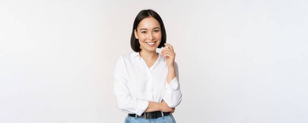 Nuori aasialainen nainen, ammatillinen yrittäjä seisoo toimistovaatteissa, hymyillen ja näyttäen itsevarmalta, valkoinen tausta - Valokuva, kuva