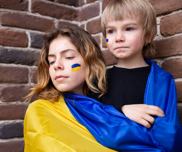 bambino e una ragazza adulta, fratello e sorella, con una bandiera ucraina blu e gialla. Famiglia, unità, sostegno, cura. Gli ucraini sono contro la guerra. stare con l'Ucraina. - Foto, immagini