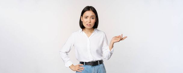 Portret van verward aziatische vrouw vragen zo wat, wat is uw probleem gebaar, staren verbaasd, clueless en geïrriteerd, staande over witte achtergrond - Foto, afbeelding