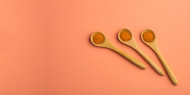 Curcuma longa - Organic turmeric powder in three wooden spoons - Foto, imagen