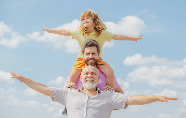 Generational famil. Father, son and grandfather happy multi genration family with raising hands or open arms flying on sky. - Zdjęcie, obraz