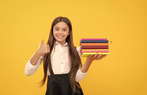 boldog tini lány az iskolában egyenruha hold book stack show hüvelykujj fel gesztus, kiválóság - Fotó, kép