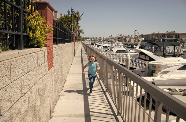 Aktif erkek çocuk yaz tatilinde gezinti güvertesinde, yaz etkinliğinde koşuyor. - Fotoğraf, Görsel