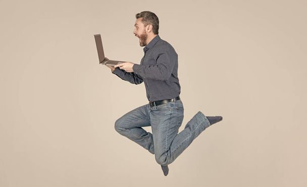 sorprendido hombre de salto enérgico que funciona en línea en el ordenador portátil prisa para ir de compras, negocio - Foto, Imagen
