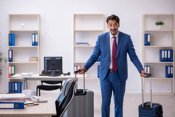 Young male employee preparing for trip at workplace - Foto, Bild