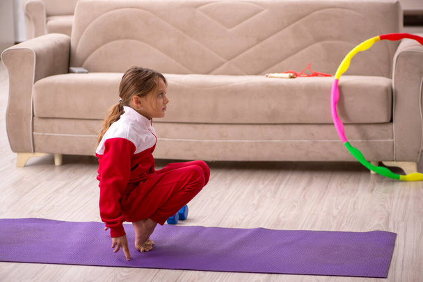 Молода дівчинка робить спортивні вправи вдома
 - Фото, зображення