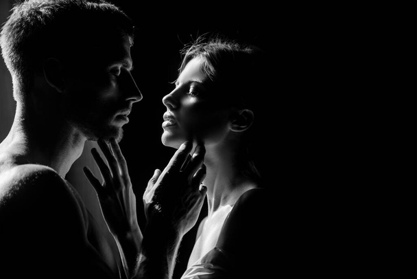 Beautiful loving couple posing on dark backgroung with night lights. Sensual portrait of a sexy couple embracing while dating. Young couple in love on black. The lovely coupl spends time together. - Zdjęcie, obraz