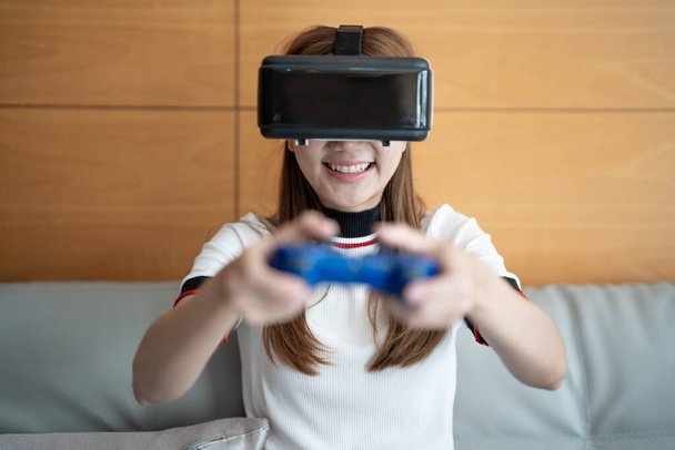 cerrar feliz emoción asiático mujer jugando video juegos con controlador en abstracto fondo tonificado con gafas virtuales - Foto, Imagen