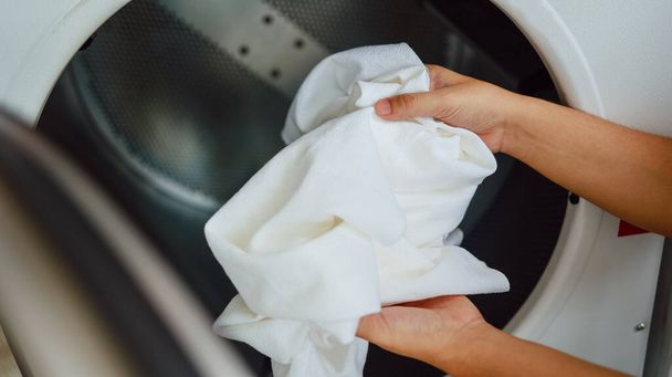 Муж с корзиной и грязным бельем стирал одежду в интерьере прачечной. стиральная машина в прачечной концепции магазина - Фото, изображение