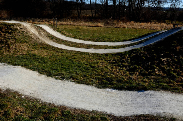race atrium bmx track voor geïmporteerde renners met glooiend terrein gekanteld spoor met bochten en sprongen. houten bruggen en hellingen zijn vrij gevaarlijk. toegang alleen voor ervaren fietsers - Foto, afbeelding