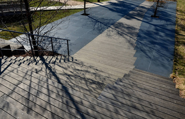 metalli ristikko lattia terassi alla puinen portaikko, joka toimii penkki tai auditorio pihalla puistossa kävelykadulla. Olen pahoillani. neliön puun kasvua reikä. ruostumattomasta teräksestä valmistetut ritilät - Valokuva, kuva