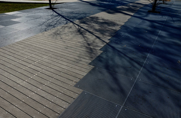 metalli ristikko lattia terassi alla puinen portaikko, joka toimii penkki tai auditorio pihalla puistossa kävelykadulla. Olen pahoillani. neliön puun kasvua reikä. ruostumattomasta teräksestä valmistetut ritilät - Valokuva, kuva