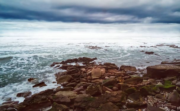 Морський пейзаж зі скелястим пляжем в штормовий день
 - Фото, зображення