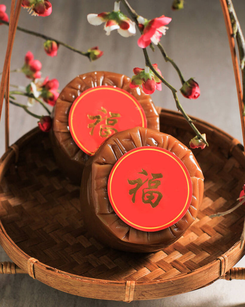 Chinese New Year Cake (with Chinese character "Fu" means Fortune). Popular as Kue Keranjang or Dodol China in Indonesia. Served on Bamboo Plate, Imlek Red Decoration - Φωτογραφία, εικόνα