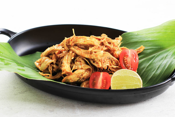 Ayam Sisit o Ayam Suwir è una cucina balinese a base di pezzi speziati di carne di pollo, servita su piatto nero. - Foto, immagini