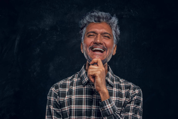 Boldog idős férfi öltözött kockás ing ellen sötét háttér - Fotó, kép