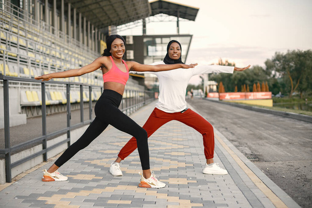 Two black women doing stretching on a stadium - Фото, изображение