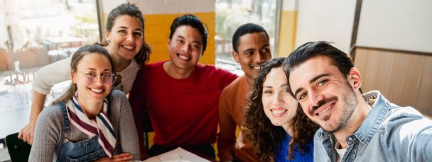 Striscione orizzontale o intestazione Gruppo multietnico di sei amici scatta una foto di selfie in un ristorante a tavola mentre mangia la pizza. Persone con felice espressione allegra - Foto, immagini