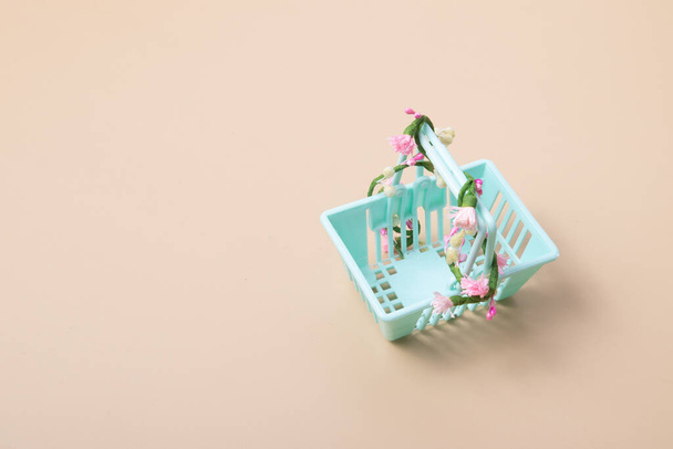Prázdný nákupní košík s květinami na béžovém pozadí. Minimalismus. Jarní prodej, nakupování, cenový koncept. - Fotografie, Obrázek