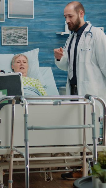 Pielęgniarka i lekarz przygotowują butelkę tabletek dla starszego pacjenta - Zdjęcie, obraz