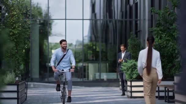 Uśmiechnięty biznesmen jeżdżący na rowerze w nowoczesnym biurowcu. Młoda przedsiębiorczyni - Materiał filmowy, wideo