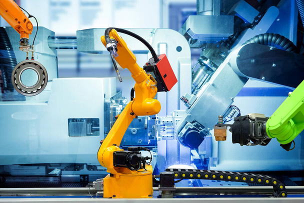 Промышленный сварочный робот и захватывающий робот, работающий с металлическими деталями на смарт-заводе, на фоне синего цвета машины, промышленности 4.0 и AI, автоматизированная роботизированная работа без контроля людей  - Фото, изображение