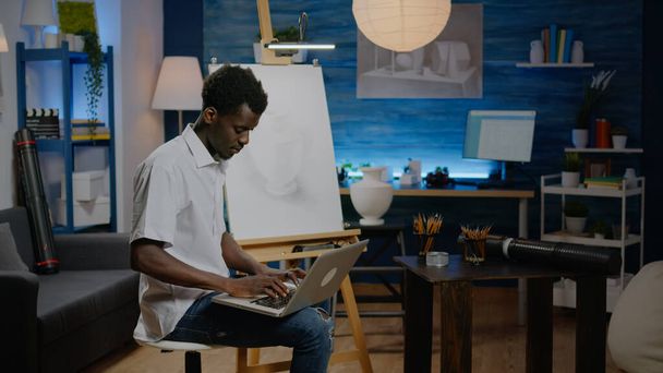 Afrikaanse Amerikaanse kunstenaar man op zoek naar inspiratie op laptop - Foto, afbeelding