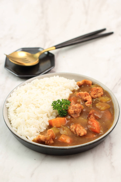 Japán vagy koreai curry rizzsel - japán ételstílus. Kerámia tányéron tálalva Fehér márvány asztalon, burgonyával, ropogós csirkés popcornnal és kockás répával, szövegmásolási hellyel. - Fotó, kép