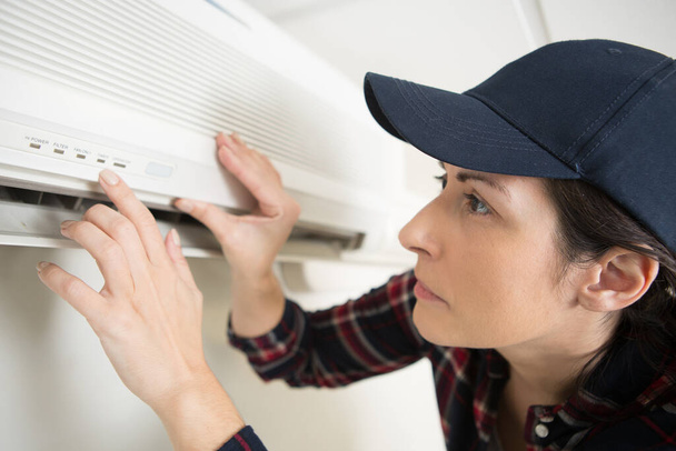 mujer trabajadora está inspeccionando el aire acondicionado - Foto, imagen