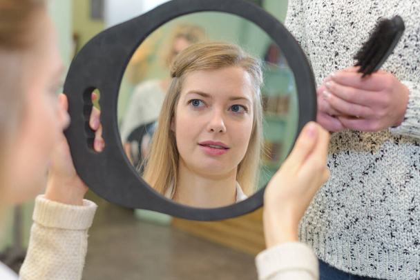young woman checks her hair in the mirror - Фото, зображення