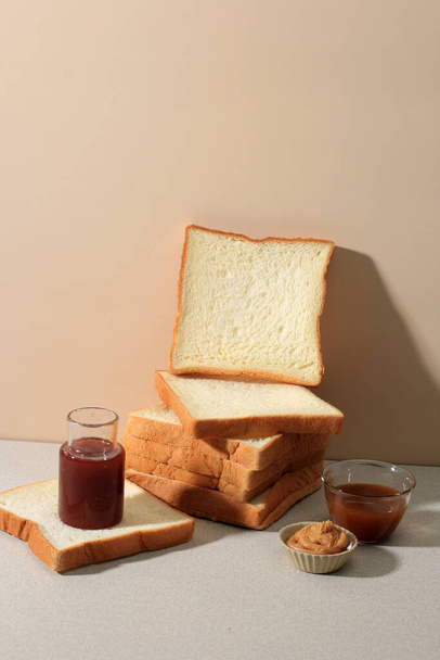Sliced Toast Loaf White Bread (Shokupan or Roti Tawar) for Breakfast on Solid Cream Background, Served with Peanut Paste, Honey, and Strawberry Compote - Zdjęcie, obraz