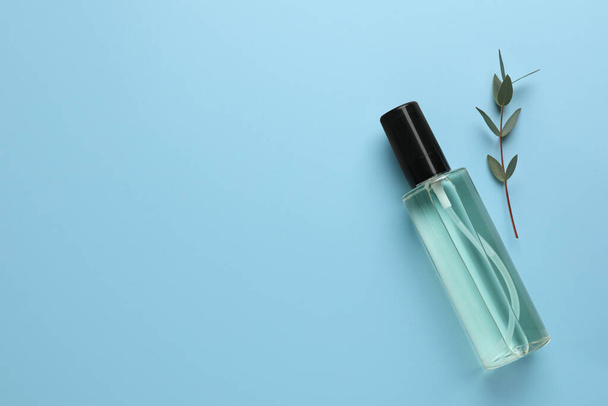 Bottle of baby oil and leaves on light blue background, flat lay. Space for text - Zdjęcie, obraz