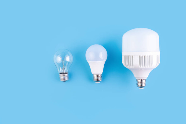incandescent lamp and led lamps against on isolated blue background. Energy efficiency concept. Flat lay. Concept ecology, save planet earth, idea, save energy, economy, saving. Earth day - 写真・画像
