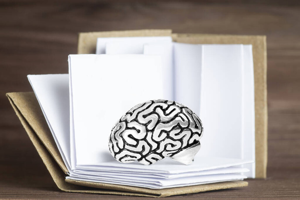 Miniature human brain model lying among open books against a wooden background. Creative studying concept. - Foto, afbeelding