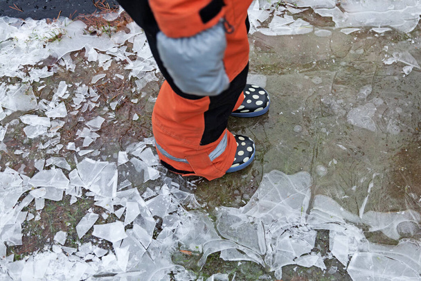 un niño en overol camina sobre hielo delgado  - Foto, imagen
