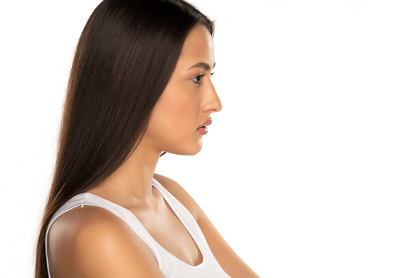 Profil d'une jeune femme aux longs cheveux noirs sur fond blanc - Photo, image