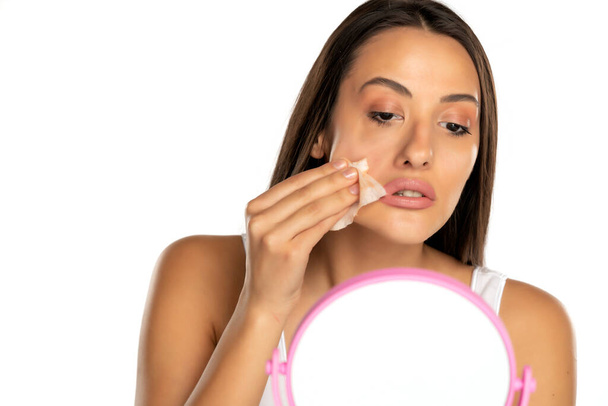 jeune femme nettoie son visage avec des lingettes humides sur fond blanc - Photo, image