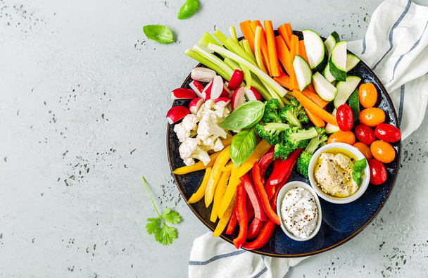 Mix of fresh, colorful, raw, sliced vegetables and dips on the plate. Healthy dietetic vegetarian or vegan party snack. Captured from above (top view, flat lay). Layout with free copy (text) space. - Foto, imagen