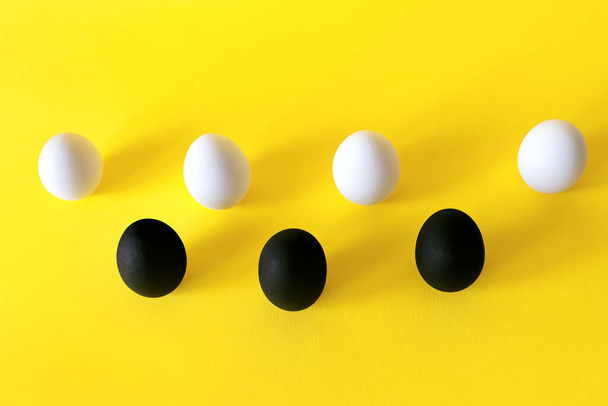 Huevos blancos y negros sobre fondo amarillo. - Foto, imagen