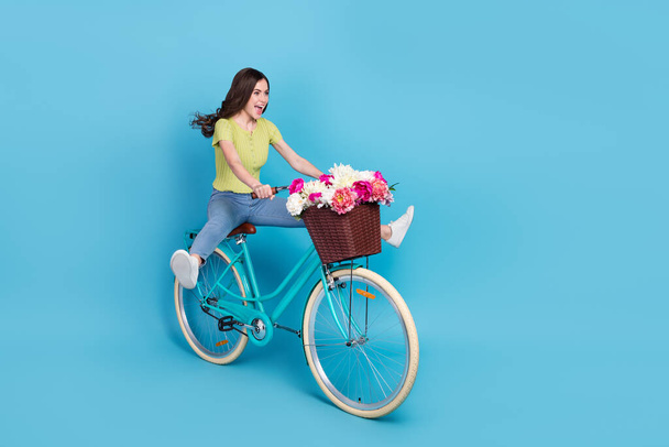Full body photo of pretty young brunette lady go by bicycle wear t-shirt jeans shoes isolated on blue background - Φωτογραφία, εικόνα