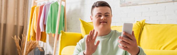 Teenager with down syndrome having video call on cellphone at home, banner  - Foto, afbeelding