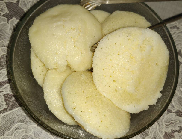 Indian idly served on transparent plate - Φρέσκος ατμός Ινδικό Idly (Idli / κέικ ρυζιού) που διοργανώνονται διακοσμητικά. Χρησιμοποιούμενο φυσικό φως. - Φωτογραφία, εικόνα