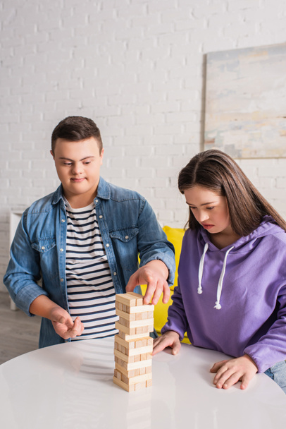 Adolescentes amigos con síndrome de Down jugando bloques de madera juego en casa  - Foto, imagen