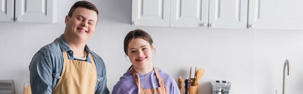 Smiling teenagers with down syndrome looking at camera in kitchen, banner  - Foto, Bild
