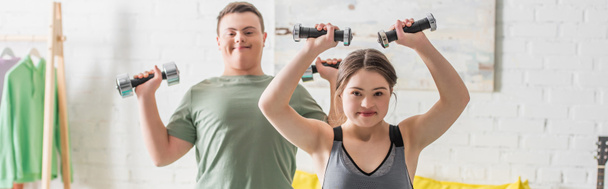 Teenager with down syndrome training with dumbbells near friend at home, banner  - Fotografie, Obrázek