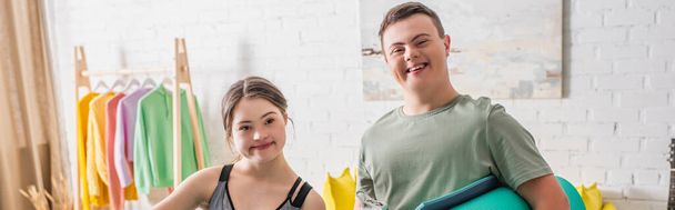 Adolescentes positivos com síndrome de down segurando tapete de fitness em casa, banner  - Foto, Imagem