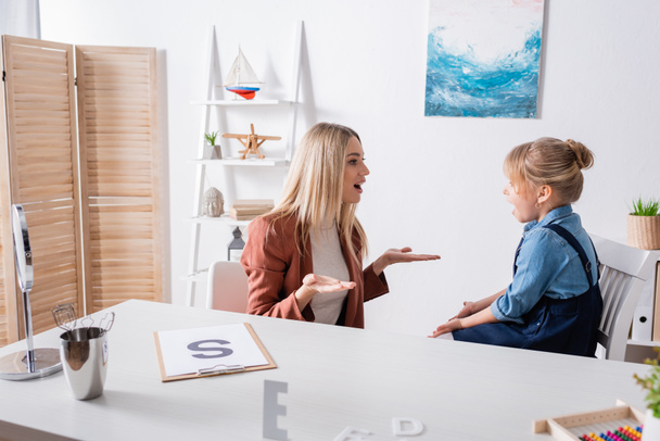 Terapeuta del habla hablando durante la lección con la chica en la sala de consulta  - Foto, imagen